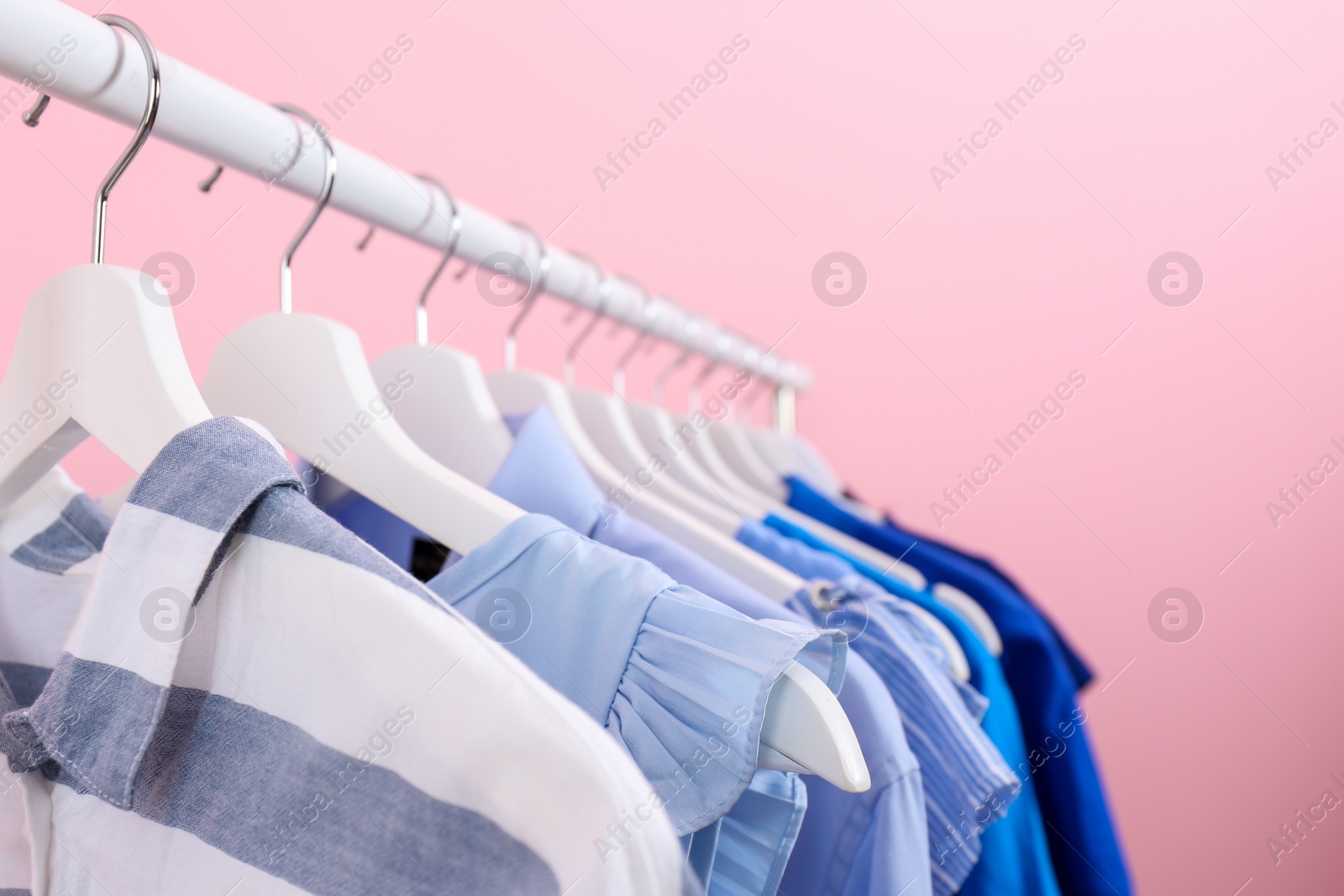 Photo of Rack with bright clothes on color background