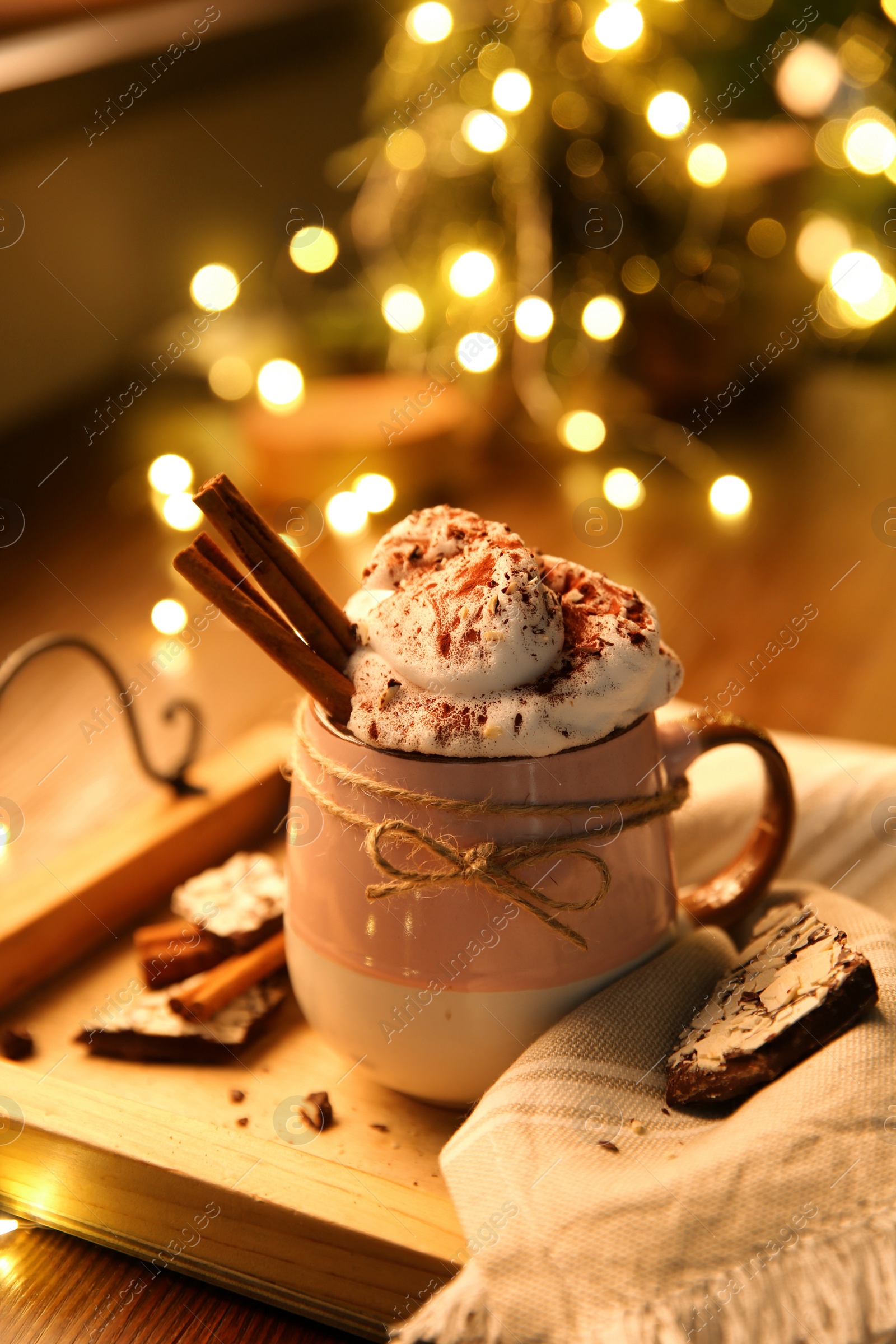 Photo of Tasty hot drink with whipped cream and Christmas lights on table