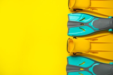 Photo of Different flippers on yellow background, flat lay. Space for text