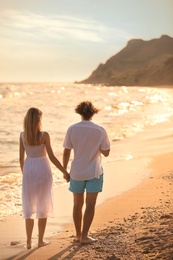 Photo of Young couple walking on beach at sunset