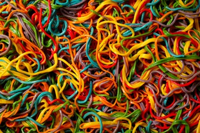 Photo of Spaghetti painted with different food colorings as background, top view