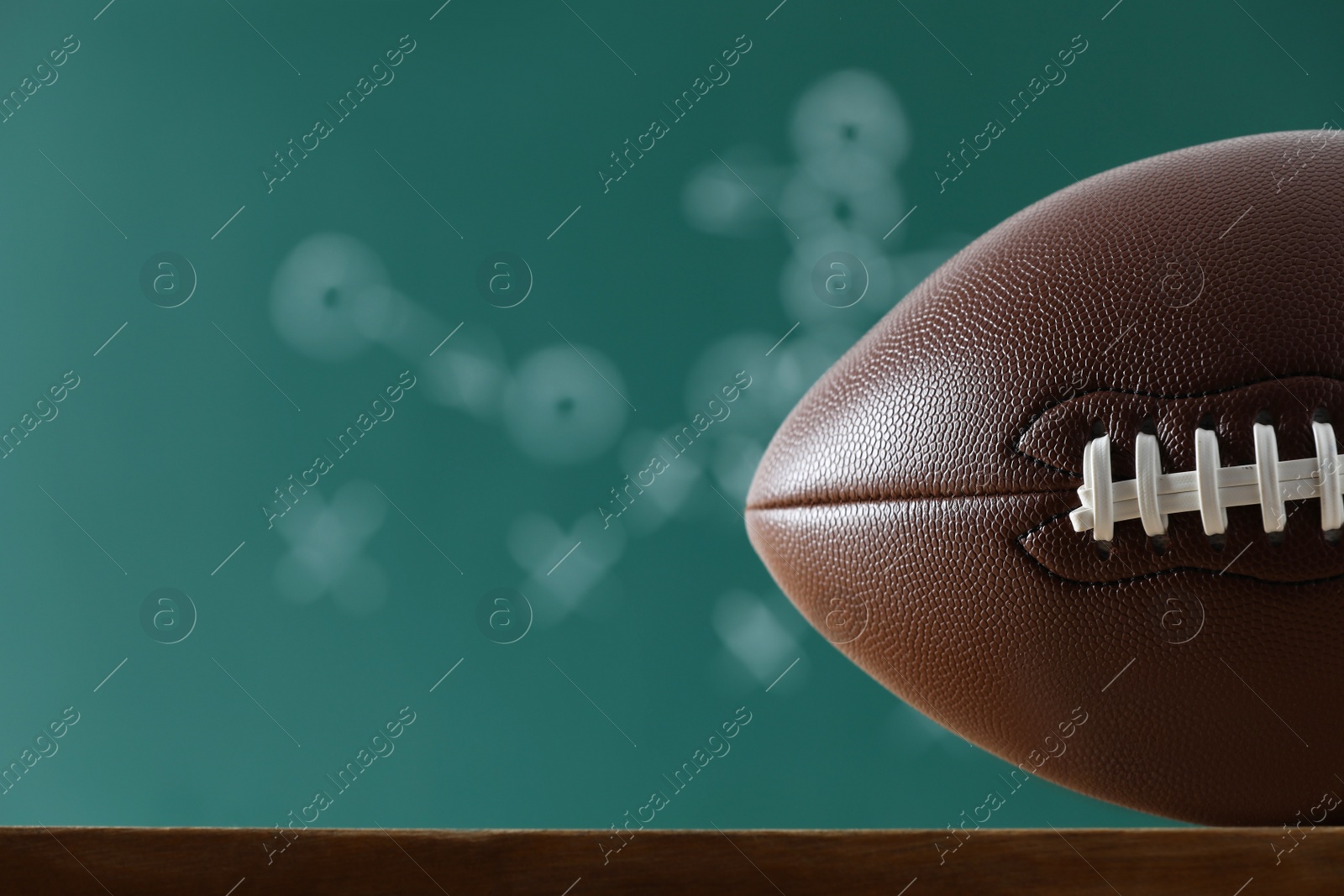 Photo of American football ball against blurred game scheme. Space for text