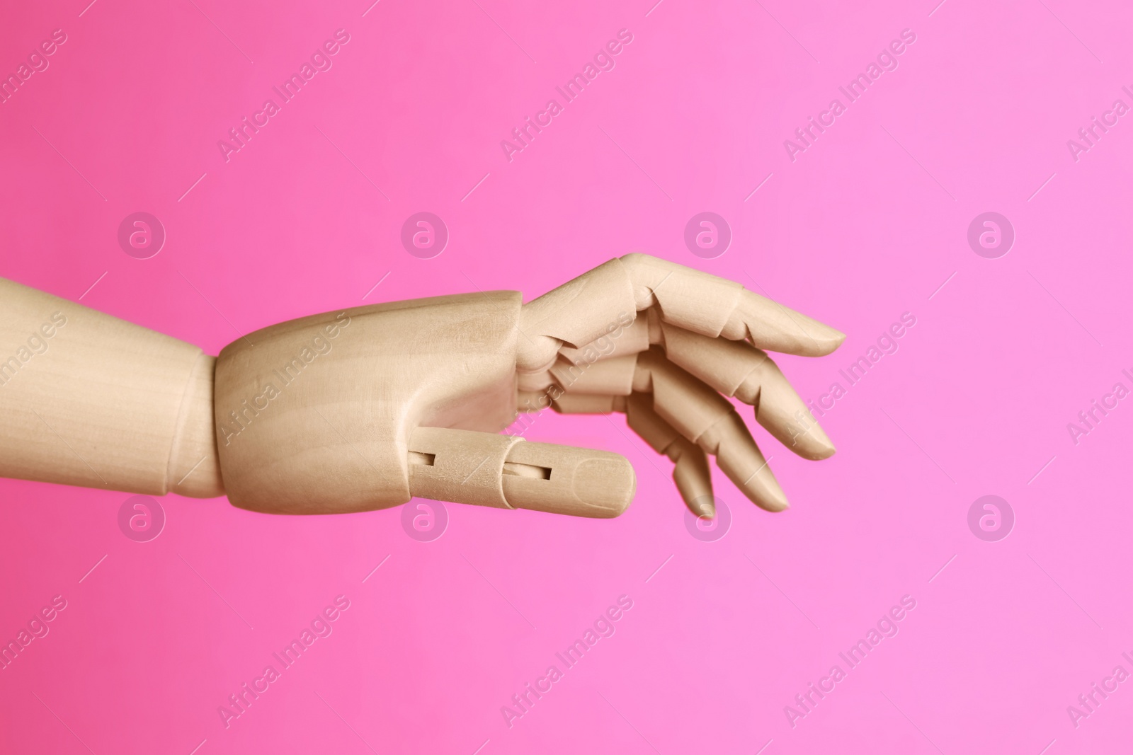 Photo of Wooden hand model on pink background. Mannequin part