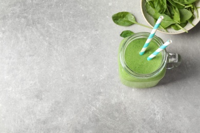 Flat lay composition with fresh green healthy spinach smoothie on grey table. Space for text