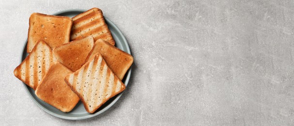Slices of tasty toasted bread on light grey table, top view with space for text. Banner design