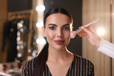 Photo of Makeup artist working with beautiful woman in dressing room
