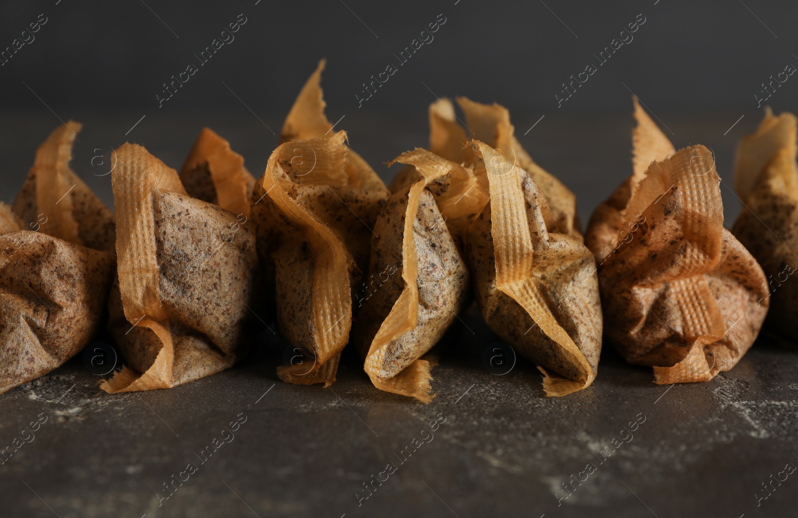 Photo of Many used tea bags on black table, closeup