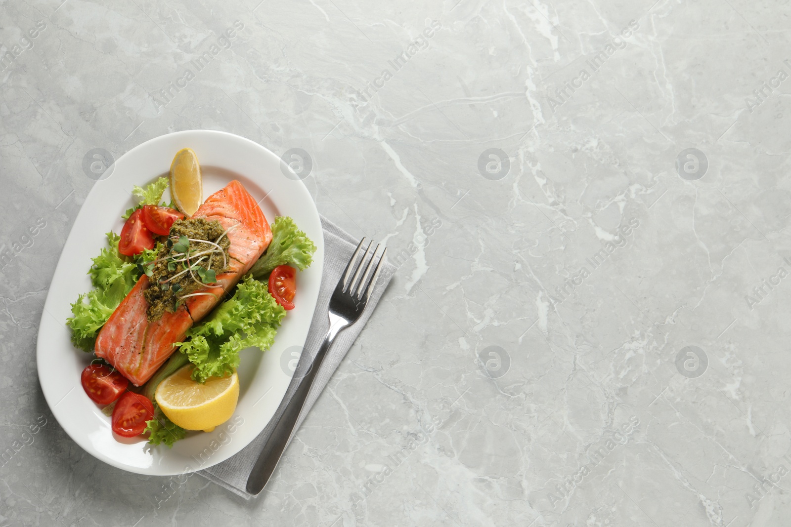 Photo of Tasty cooked salmon with pesto sauce and fresh salad on grey table, flat lay. Space for text