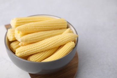 Photo of Tasty fresh yellow baby corn in bowl on white table, space for text