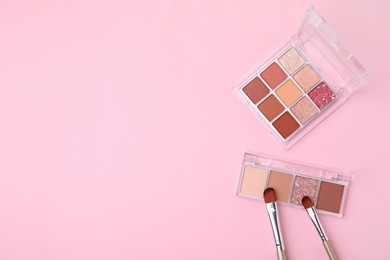 Photo of Beautiful eye shadow palettes and brushes on pink background, flat lay. Space for text