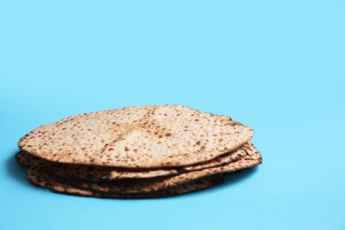 Photo of Tasty matzos on light blue background, space for text. Passover (Pesach) celebration