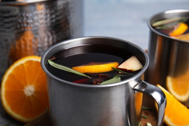 Photo of Tasty mulled wine with spices in mug on table, closeup