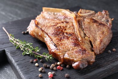 Delicious fried beef meat, thyme and peppercorns on table, closeup