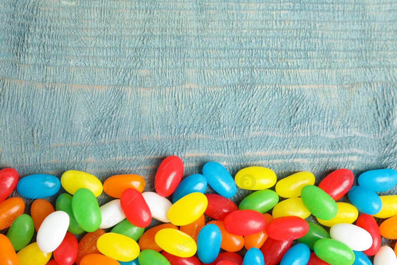 Photo of Flat lay composition with jelly beans on color background. Space for text