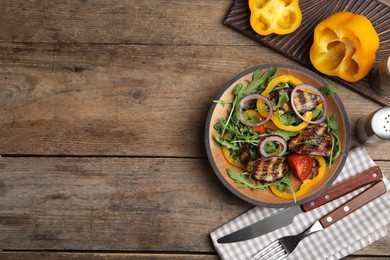 Photo of Delicious salad with roasted eggplant and arugula served on wooden table, flat lay. Space for text