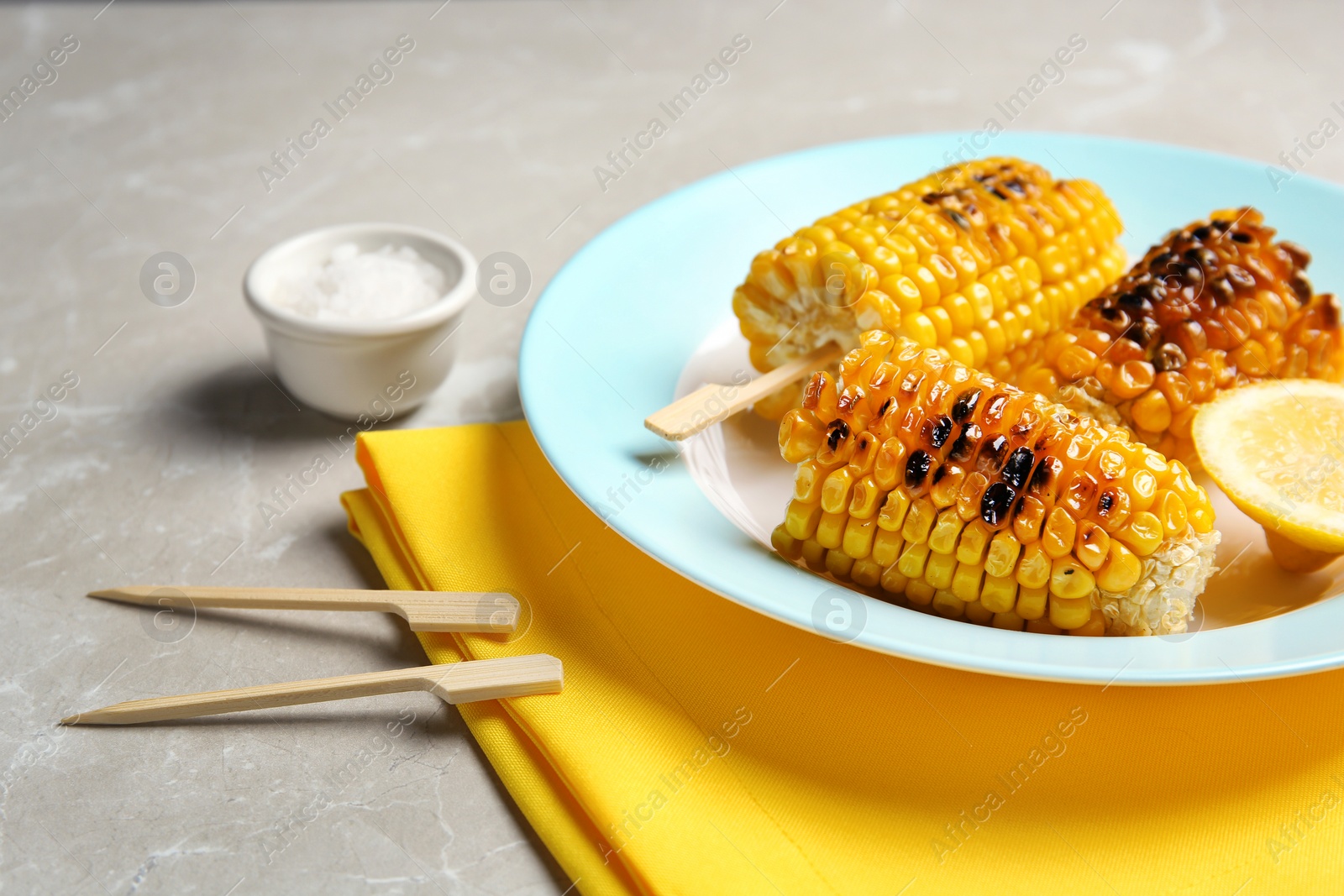 Photo of Plate with delicious grilled corn cobs on light table