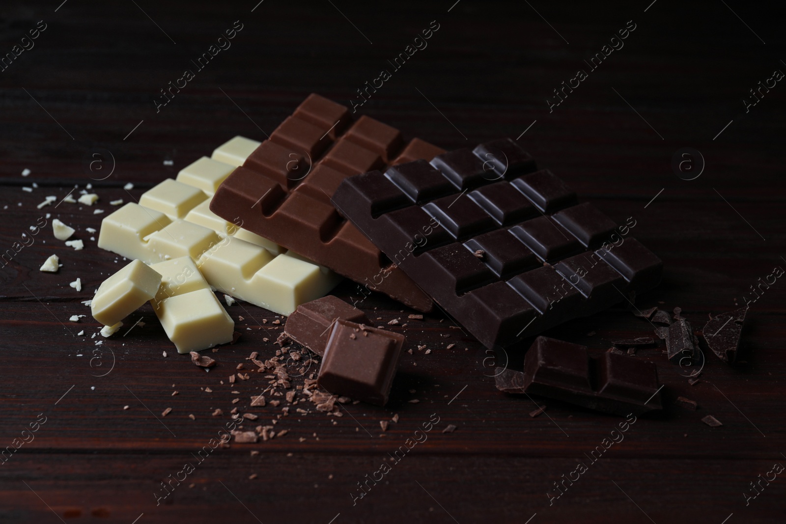 Photo of Different tasty chocolate bars on wooden table