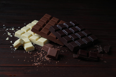 Different tasty chocolate bars on wooden table