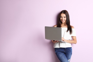 Young woman with modern laptop on color background