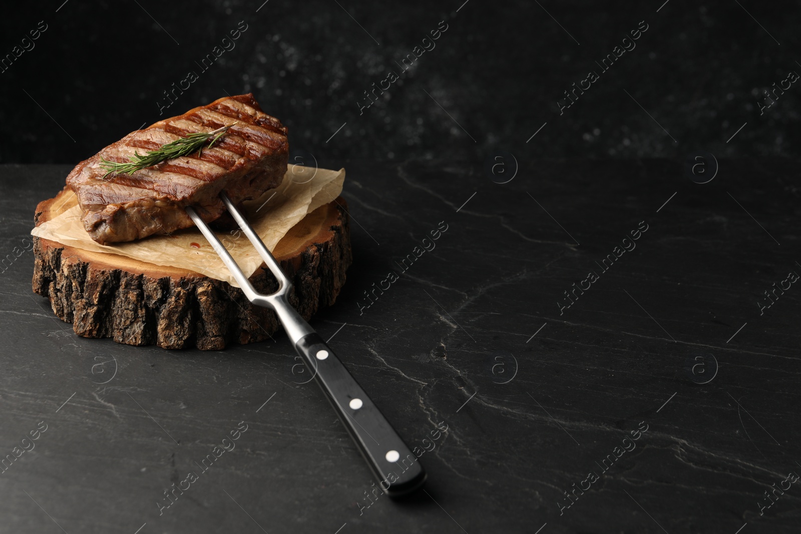 Photo of Delicious grilled beef steak served with rosemary on dark gray table, space for text