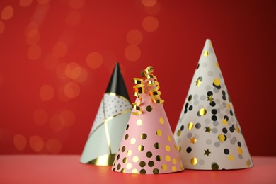 Photo of Beautiful party hats and serpentine streamers on red background, space for text