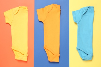Different baby bodysuits on color background, flat lay