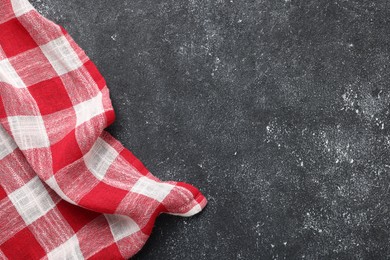 Red checkered tablecloth on black textured table, top view. Space for text