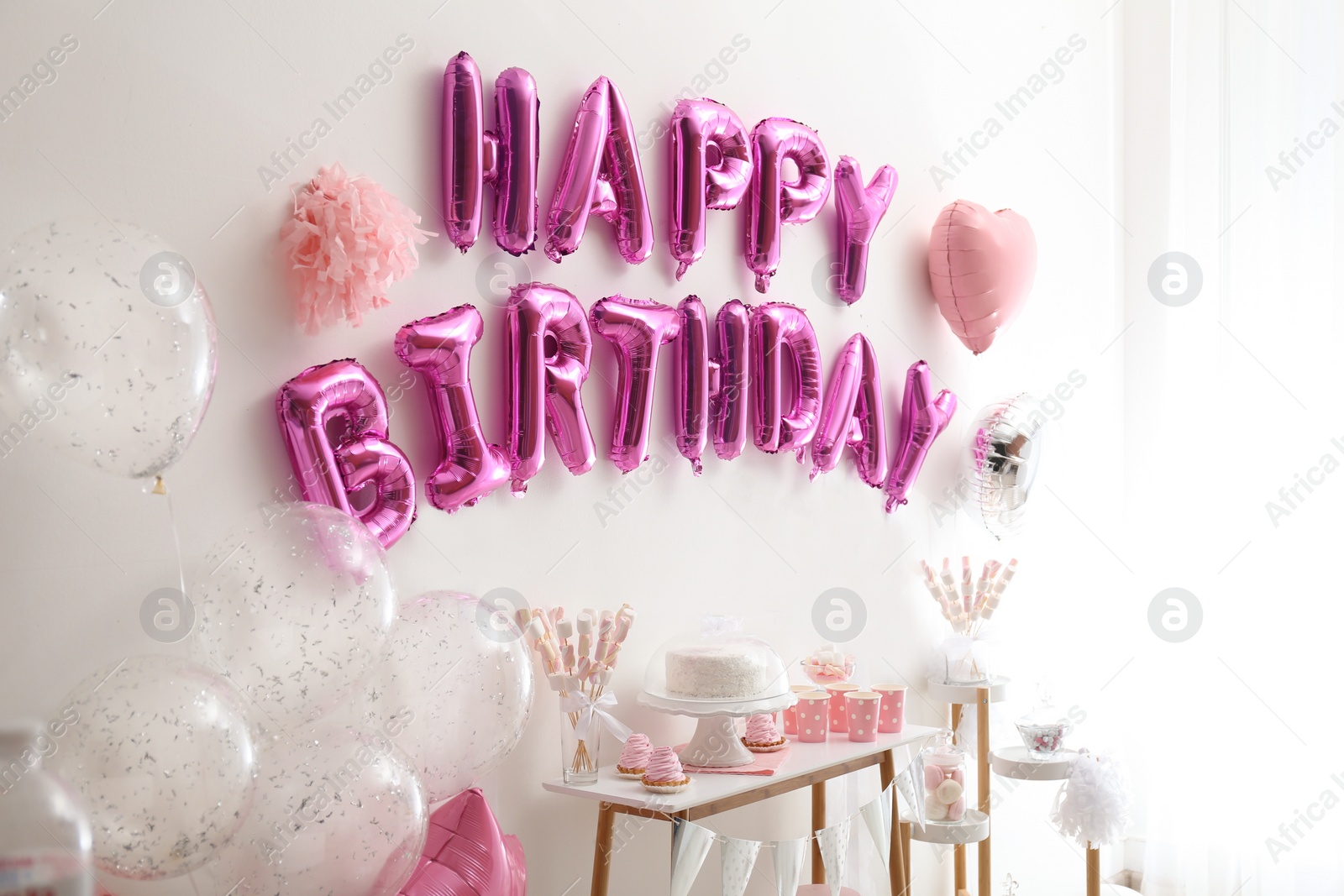 Photo of Phrase HAPPY BIRTHDAY made of pink balloon letters in decorated room