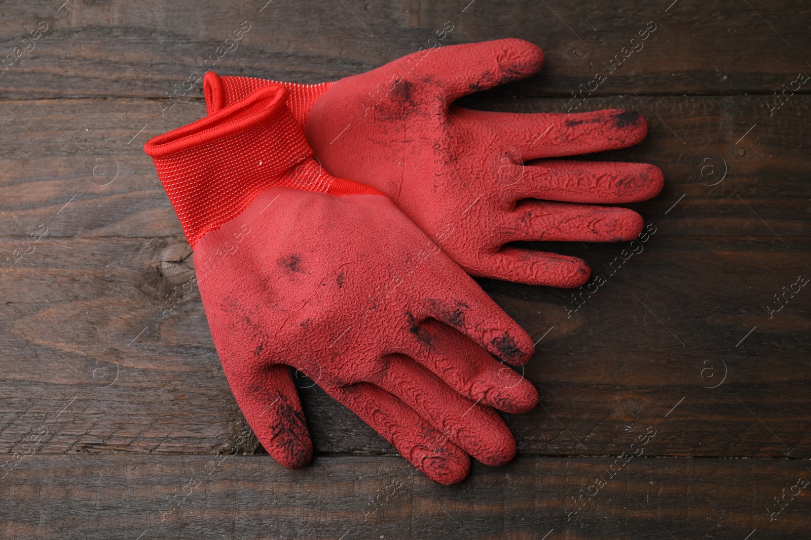Photo of Pair of red gardening gloves on wooden table, top view