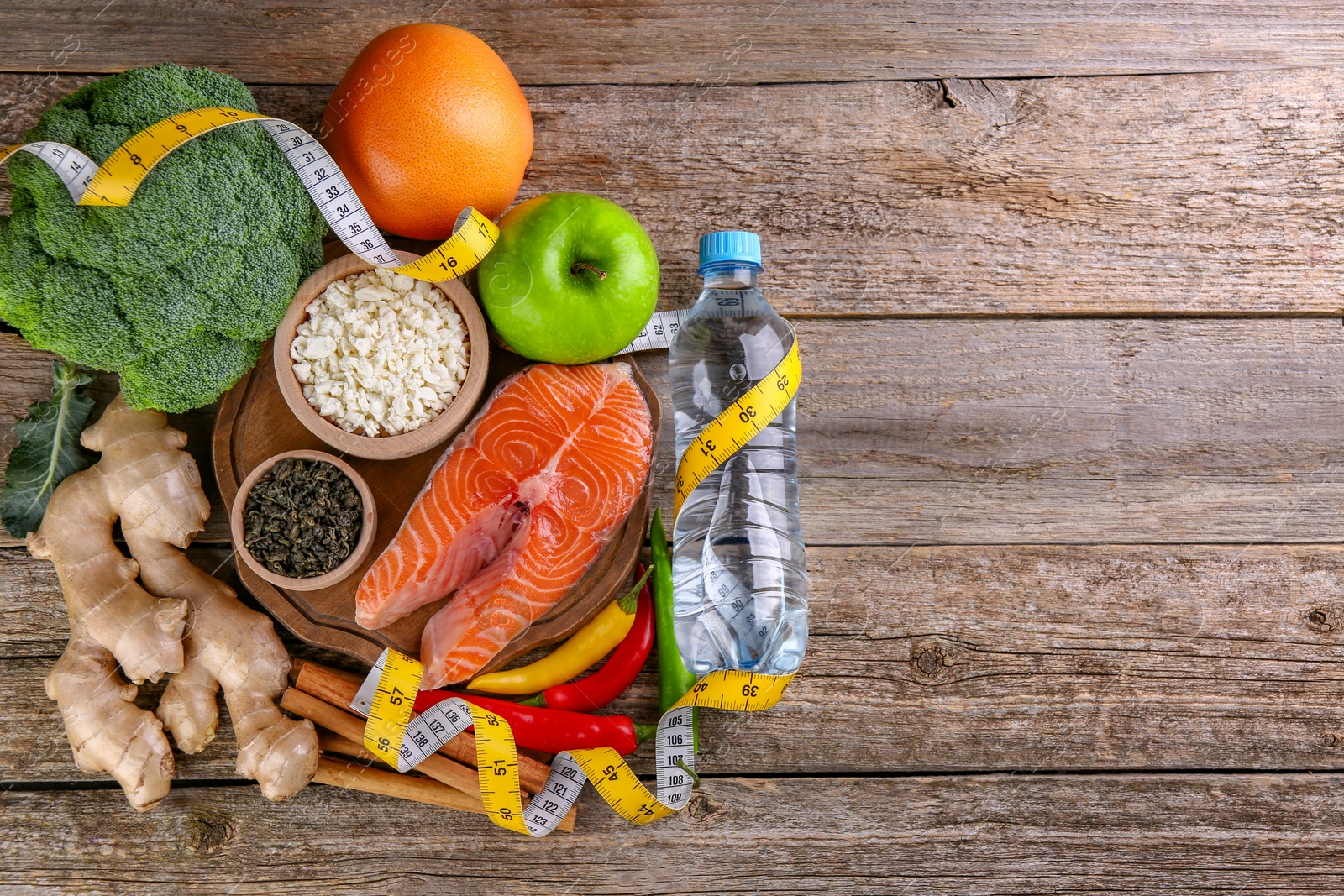 Photo of Metabolism. Different food products and measuring tape on wooden table, flat lay with space for text