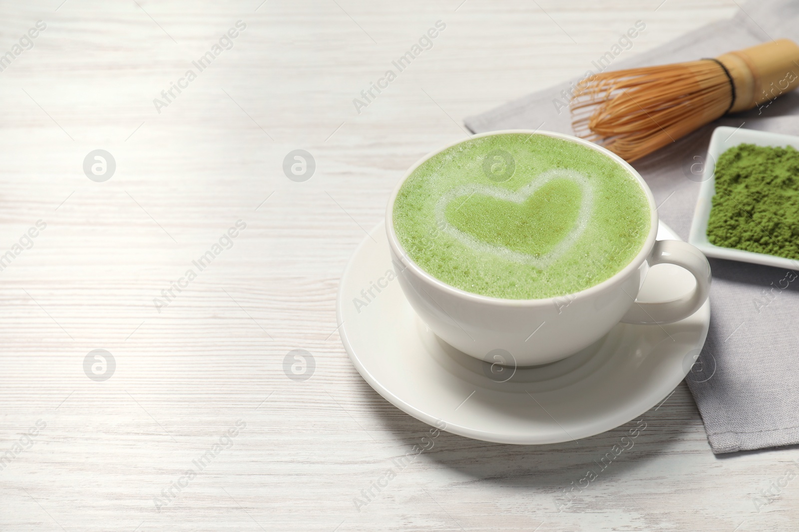 Photo of Cup of tasty matcha latte on white wooden table, space for text