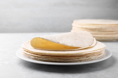 Plate with stack of tasty tortillas on grey table. Space for text