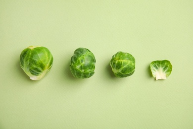 Photo of Fresh Brussels sprouts on green background, flat lay