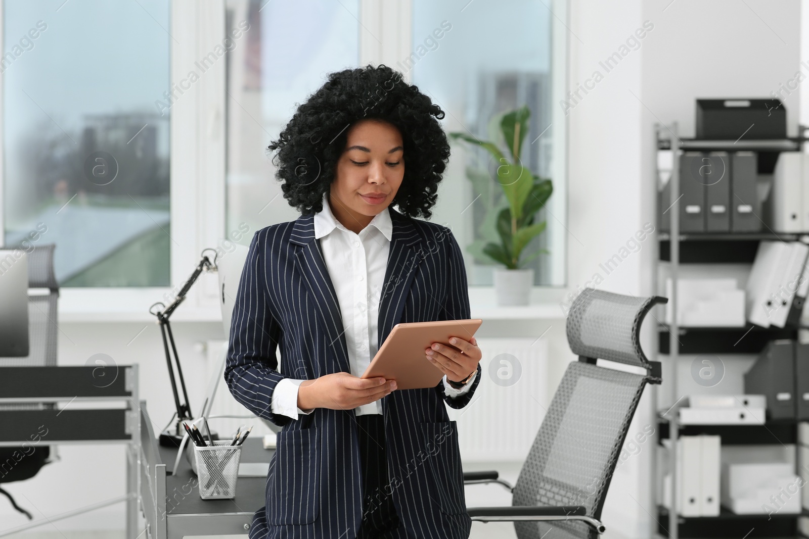 Photo of Young businesswoman using tablet in modern office