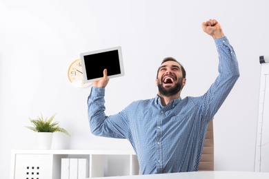 Emotional young man with tablet celebrating victory in office