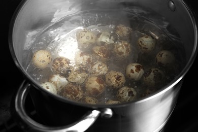 Cooking quail eggs in pot on electric stove, closeup