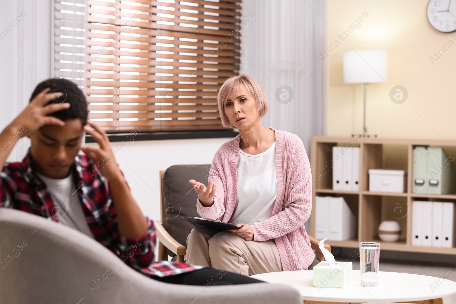 Photo of Psychotherapist working with teenage African-American boy in office