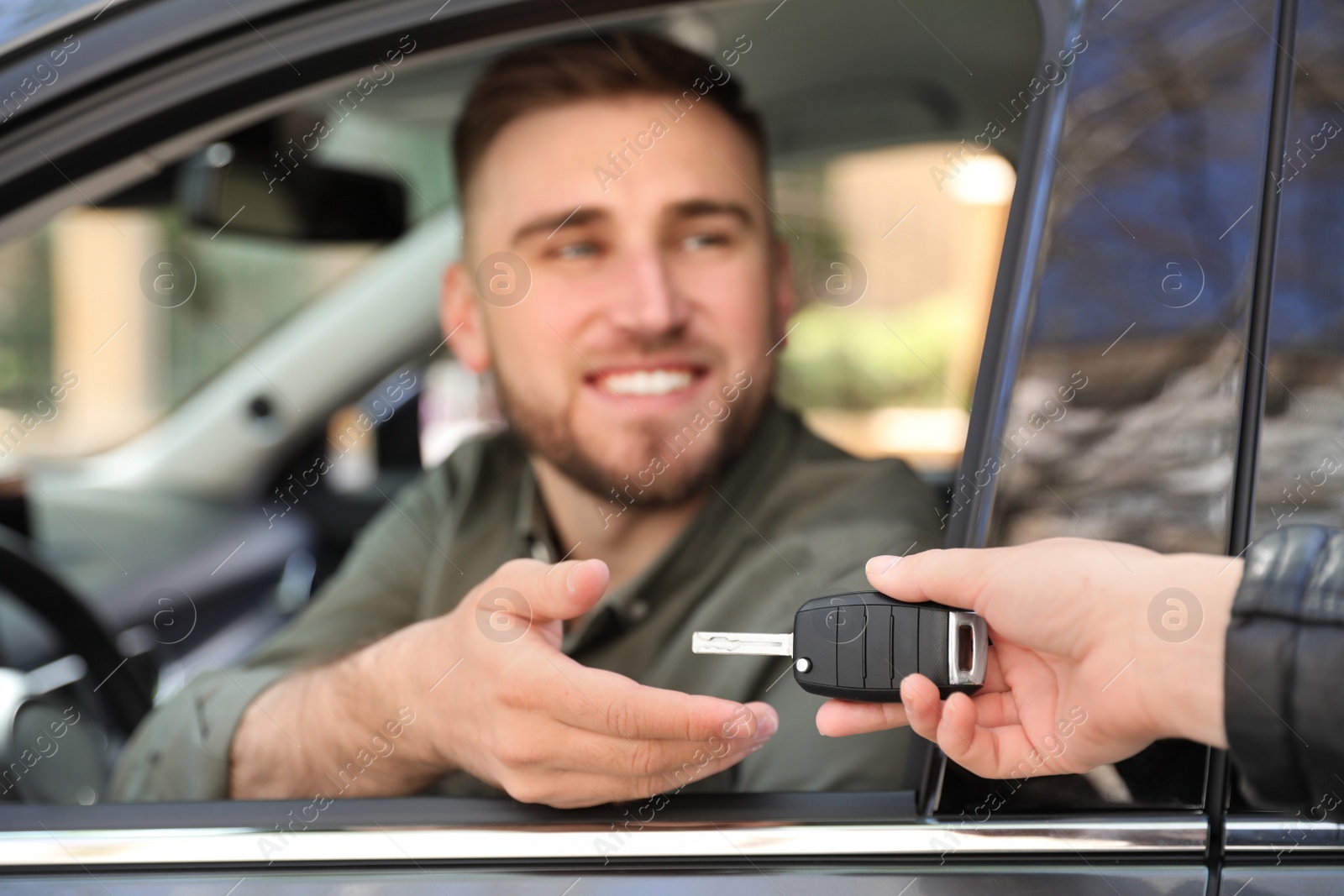 Photo of Salesperson giving car key to customer outdoors