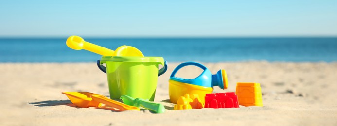 Different child plastic toys on sandy beach. Banner design