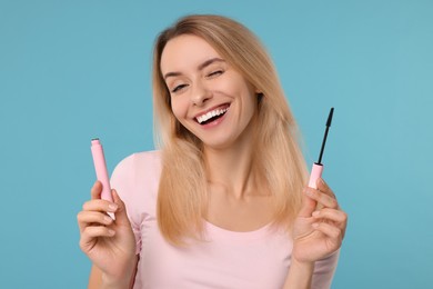 Beautiful woman with mascara on light blue background