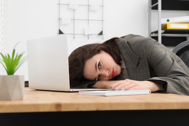 Photo of Depressed intern lying on table in modern office. First work day