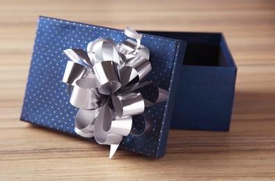 Open empty gift box with bow on wooden table