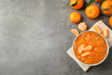 Flat lay composition with tasty tangerine jam on grey table. Space for text