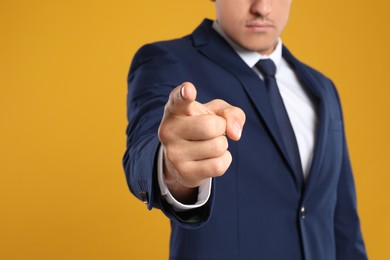 Photo of Businessman touching something on yellow background, closeup. Finger gesture