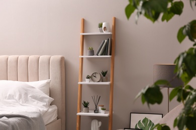 Photo of Stylish bedroom interior with decorative ladder and plants near grey wall