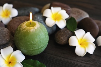 Photo of Composition with spa stones, flowers and candle on wooden background