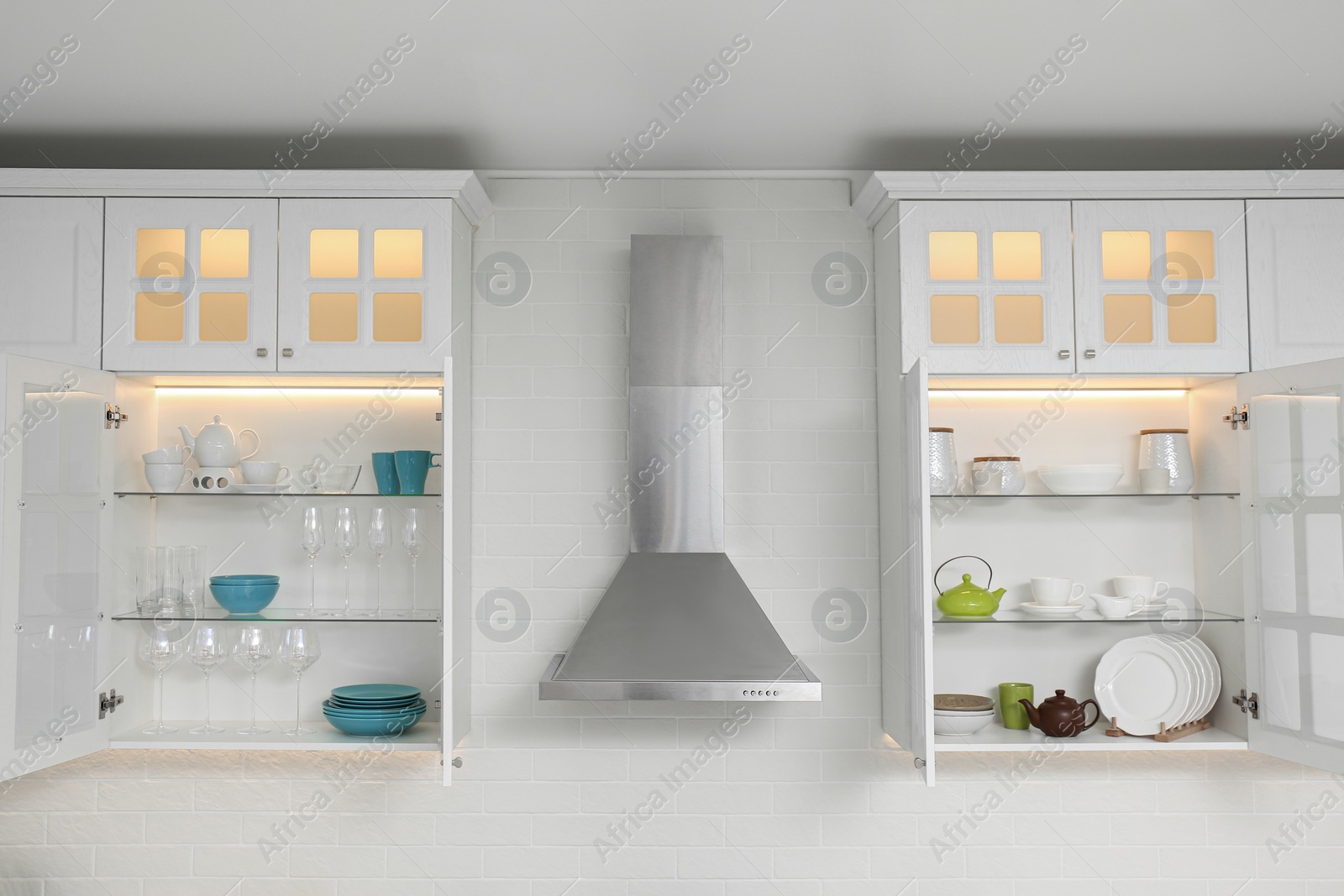 Photo of Open cabinets with different clean dishware in kitchen