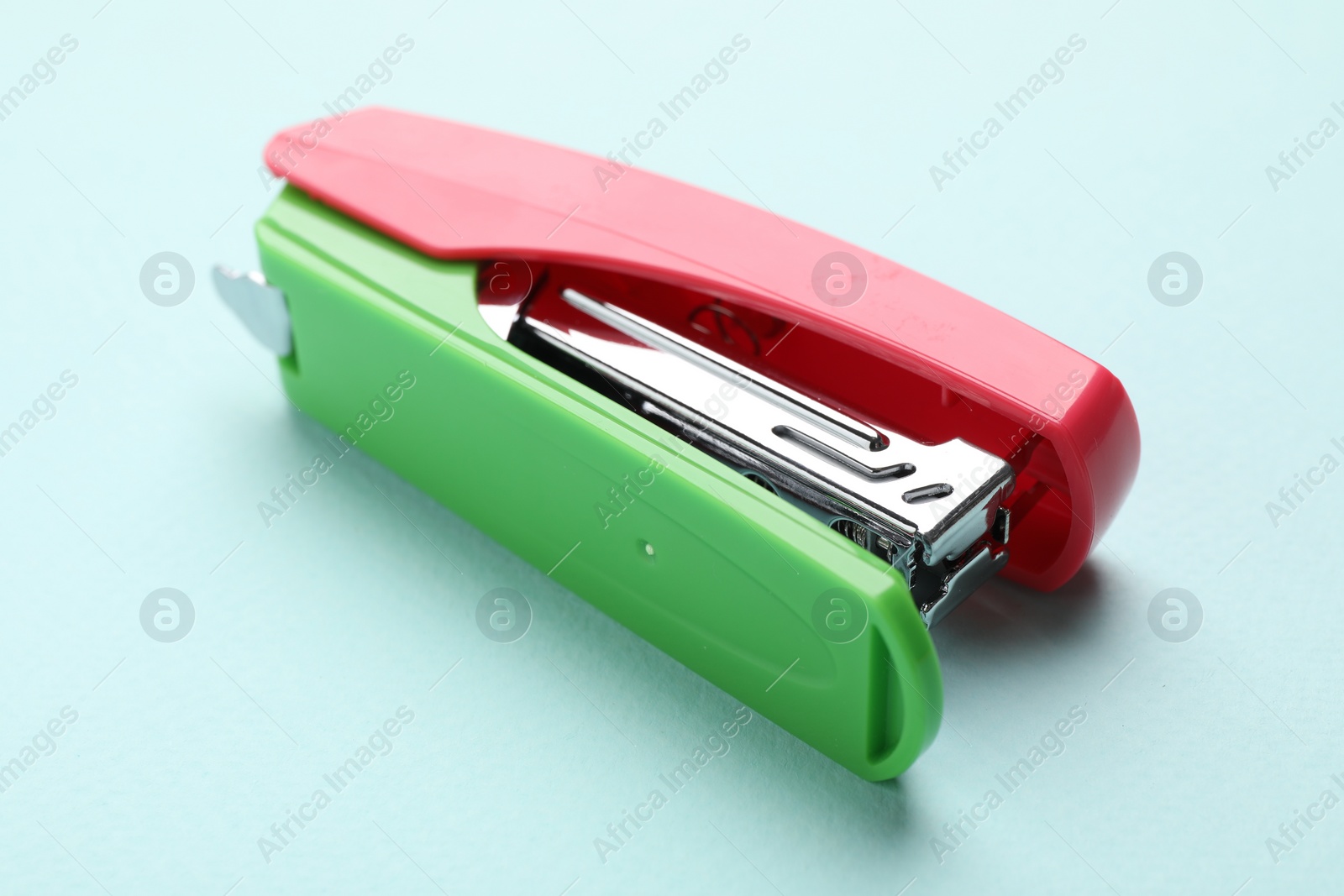 Photo of One bright stapler on light blue background, closeup