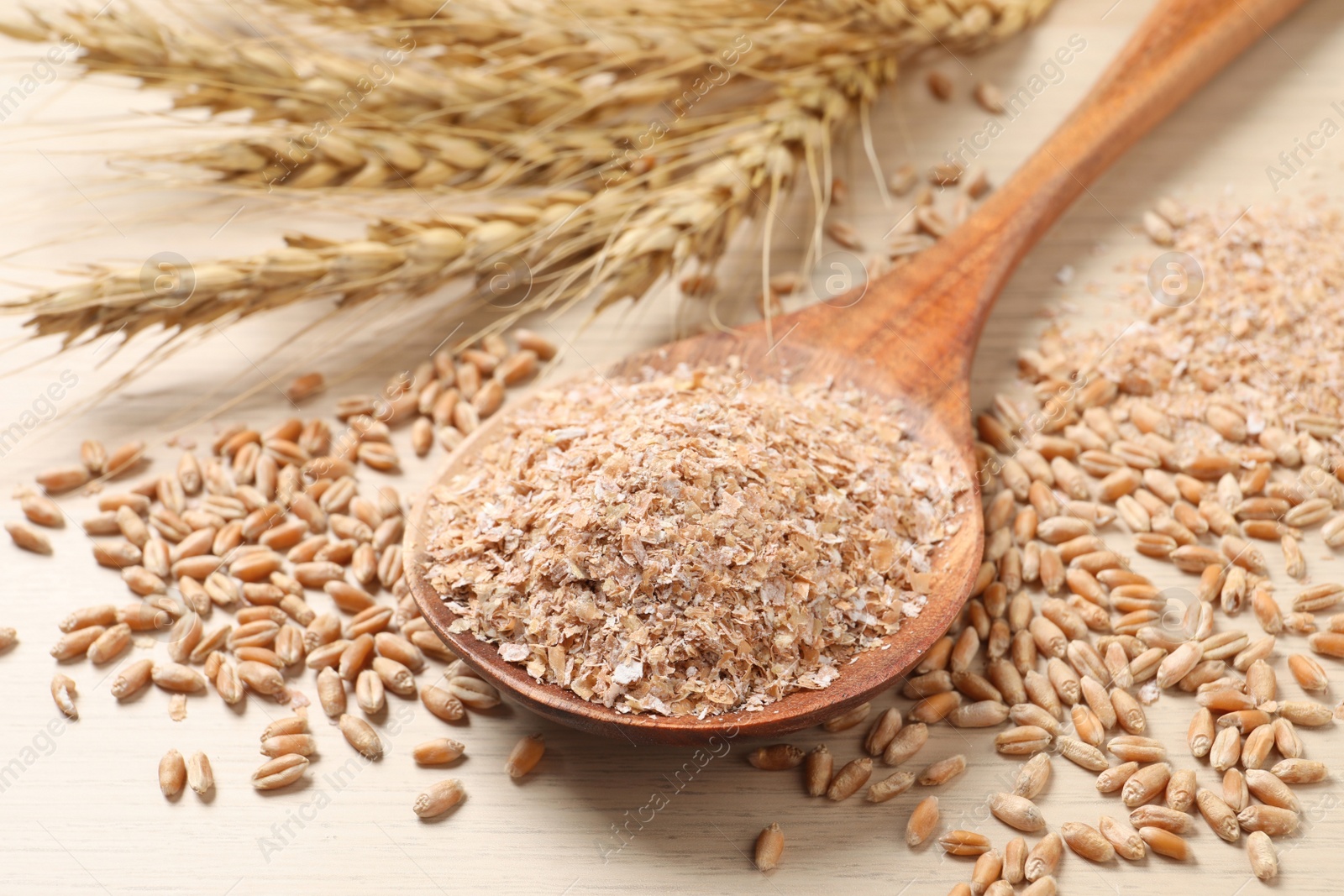 Photo of Wheat bran and kernels on wooden table, closeup