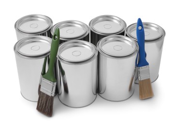 Photo of Cans of paints and brushes on white background